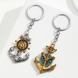 Retro nautical anchor and helm keychain in silver and gold finish on a white stand