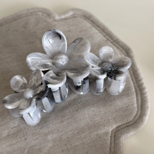 Détail d'une pince à cheveux fleurie avec motif marbré gris et finition brillante