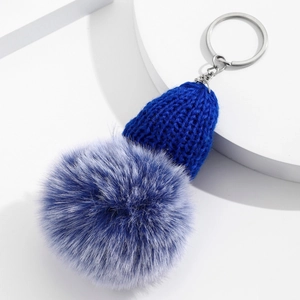 Détail macro du bonnet en tricot bleu roi et du pompon en fausse fourrure pour sac