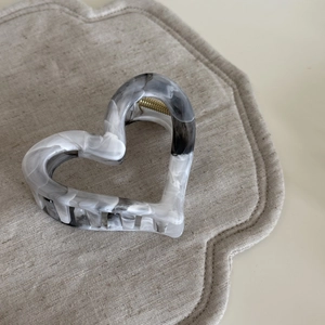 Détail d'une pince à cheveux en forme de cœur en acétate avec motif de marbre gris