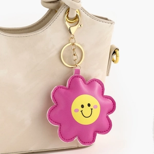 Détail d'un porte-clés fleur en cuir rose avec visage souriant sur un sac à main