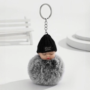 Détail du porte-clés bébé endormi avec bonnet noir et pompon en fausse fourrure grise