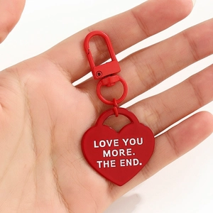 Dettaglio portachiavi a cuore in metallo rosso con scritta LOVE YOU MORE incisa