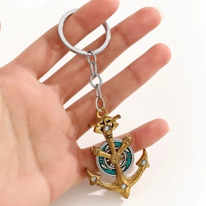 Detail of hand-held vintage bronze anchor keychain with nautical helm and enamel inlay