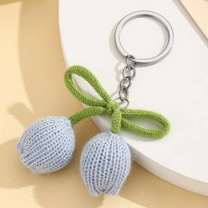 Detailed view of hand-knitted light blue tulip buds with green stem and bow on a keychain