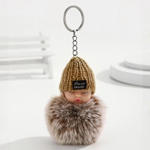 Détail d'un porte-clés poupée bébé en peluche avec bonnet jaune et étiquette