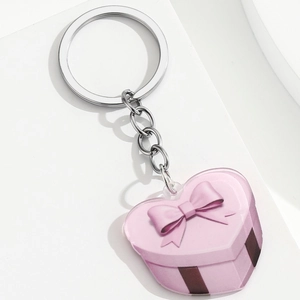 Detail view of pink heart acrylic keychain featuring festive gift box and bow printing