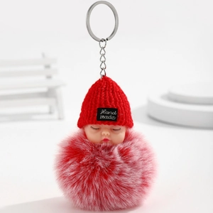 Détail d'un porte-clés poupée bébé endormie rouge avec pompon en fausse fourrure
