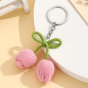 Close-up of handmade knitted pink tulip flower keychain with green bow and silver ring