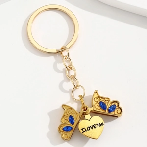 Vue détaillée du porte-clés papillon doré avec strass bleus et pendentif gravé I Love You