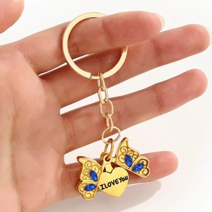 Pendentif cœur avec gravure I Love You et porte-clés papillon en cristal bleu tenu à la main