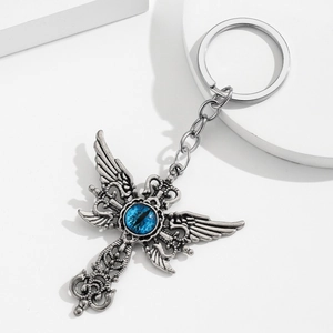 Porte-clés croix gothique argentée avec ailes d'ange et œil bleu sur fond blanc épuré