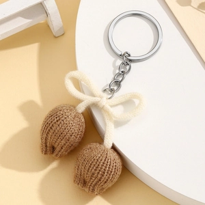 Detail of hand-knitted brown tulip keychain with creamy white bow and silver metal ring