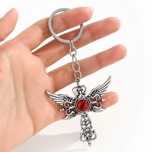 Vue détaillée d'une croix gothique argentée vintage avec ailes et œil rouge