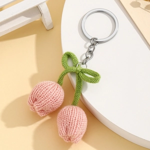 Detailed macro view of hand-knitted pink tulip pendant with a green bow on a key ring