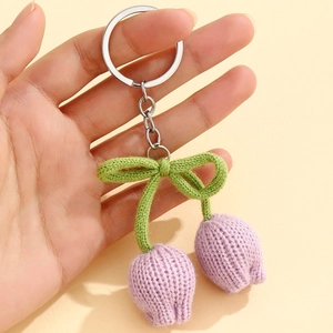 Detailed macro shot of handmade knitted purple tulip keychain with a silver ring held in hand