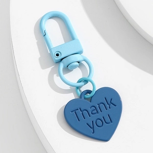 Détail macro d'un porte-clés coeur bleu avec gravure Thank You sur la surface mate