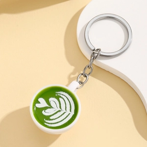 Detail showing miniature matcha latte art cup keychain with heart design and silver metal ring