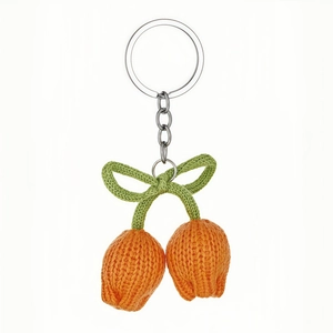 Handmade knitted orange tulip flower keychain with green leaves on white background