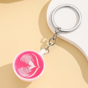 Macro view of pink latte art coffee cup keychain with a delicate heart pattern detail