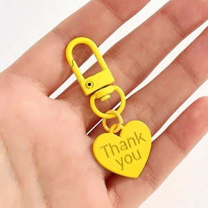 Porte-clés cœur jaune avec gravure Thank You présenté dans la main d'un homme