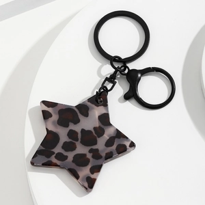 Detail van ster sleutelhanger met luipaardprint en zwarte metalen sluiting op wit