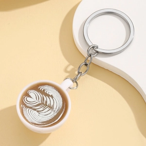 Detailed macro shot of miniature coffee cup keychain with leaf pattern latte art design