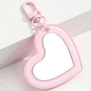 Detail of pink heart-shaped acrylic mirror pendant with metallic lobster clasp on white steps