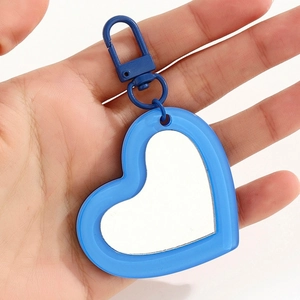 Blue heart mirror pendant with metal lobster clasp held in hand for scale detail