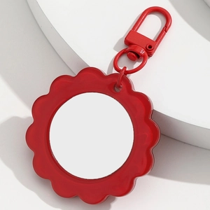Detail view of red flower-shaped pocket mirror with metal lobster clasp and white insert