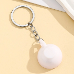 Detail view of miniature white latte art coffee cup keychain with silver metal ring