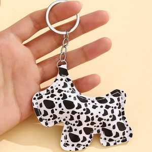 Porte-clés chien Scottish Terrier en similicuir à motif vache noir et blanc tenu en main