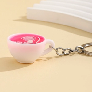Miniature pink glowing coffee cup keychain with white heart latte art on white steps