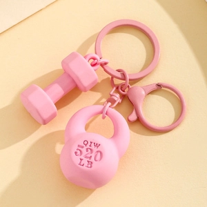 Pink fitness keychain featuring mini dumbbell and kettlebell charms on beige background