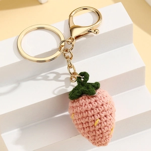 Detail van handgebreide roze aardbei sleutelhanger met groene blaadjes en gouden sluiting