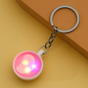 Detail shot of a creative white coffee cup keychain glowing with bright pink LED light
