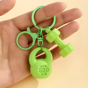 Close-up of a neon green kettlebell and dumbbell keychain with engraved 520 LB text