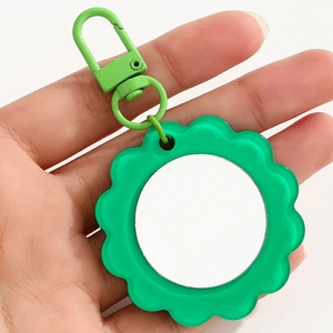 Macro view of green flower-shaped keychain mirror with metal clasp in handheld shot