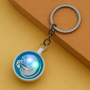 Detail of miniature coffee cup keychain with blue latte art and silver metal chain link