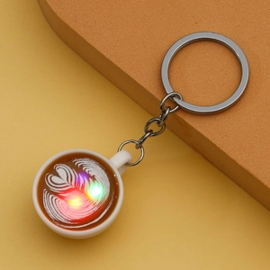 Detail showing glowing LED coffee cup keychain with latte art design and metal ring