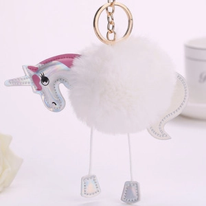 Detail of cute white plush unicorn keychain with iridescent faux leather and gold ring