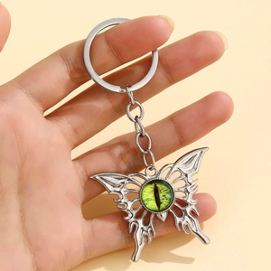Detailed macro of a silver butterfly keychain with a green devil eye bead being held