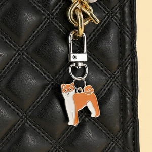 Vue macro détaillée d'un porte-clés Shiba Inu en émail sur un sac en cuir matelassé noir