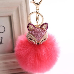 Close-up of pink faux fur fox keychain with sparkling rhinestones and golden hardware