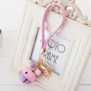 Detail of pink and purple bell keychain with leather strap and golden metal clasp