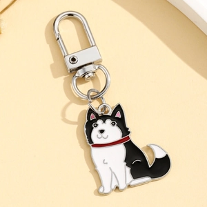 Détail d'un porte-clés husky en émail noir et blanc avec crochet en métal sur fond beige
