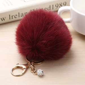 Vue détaillée du porte-clés pompon bordeaux en fausse fourrure avec fermoir doré