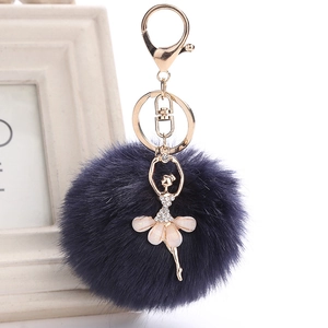 Detail of dark blue faux fur pompom with golden rhinestone ballerina charm keychain
