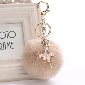 Close-up of fluffy caramel faux fur pompom keychain with rhinestone ballet dancer pendant