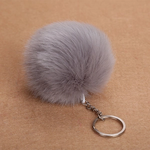 Soft grey faux fur pom pom keychain with silver metal ring on neutral background